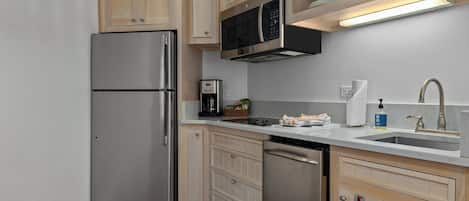 A modern kitchen with stainless steel appliances, wooden cabinets, and a built-in microwave.