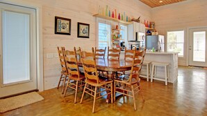 A dining area with a wooden table and chairs, a kitchen with white cabinets, and a wooden ceiling. - 6 On The Beach VW6 (Port Aransas)