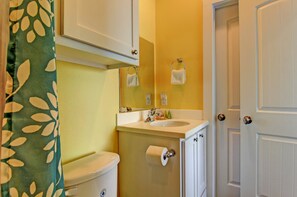 A bathroom with a toilet, sink, and mirror.