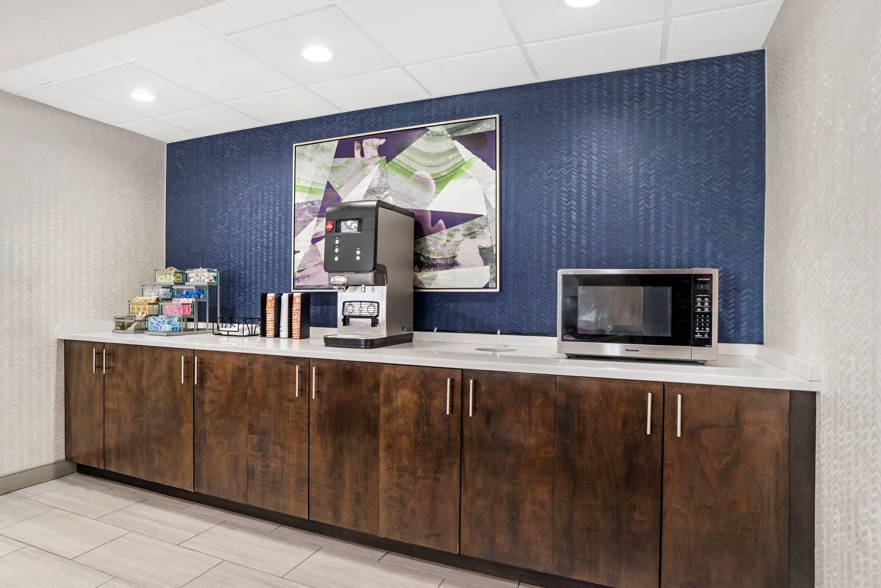 A kitchenette with a coffee maker, microwave, and cabinets.