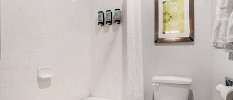 A bathroom with a bathtub, toilet, and a framed picture on the wall.