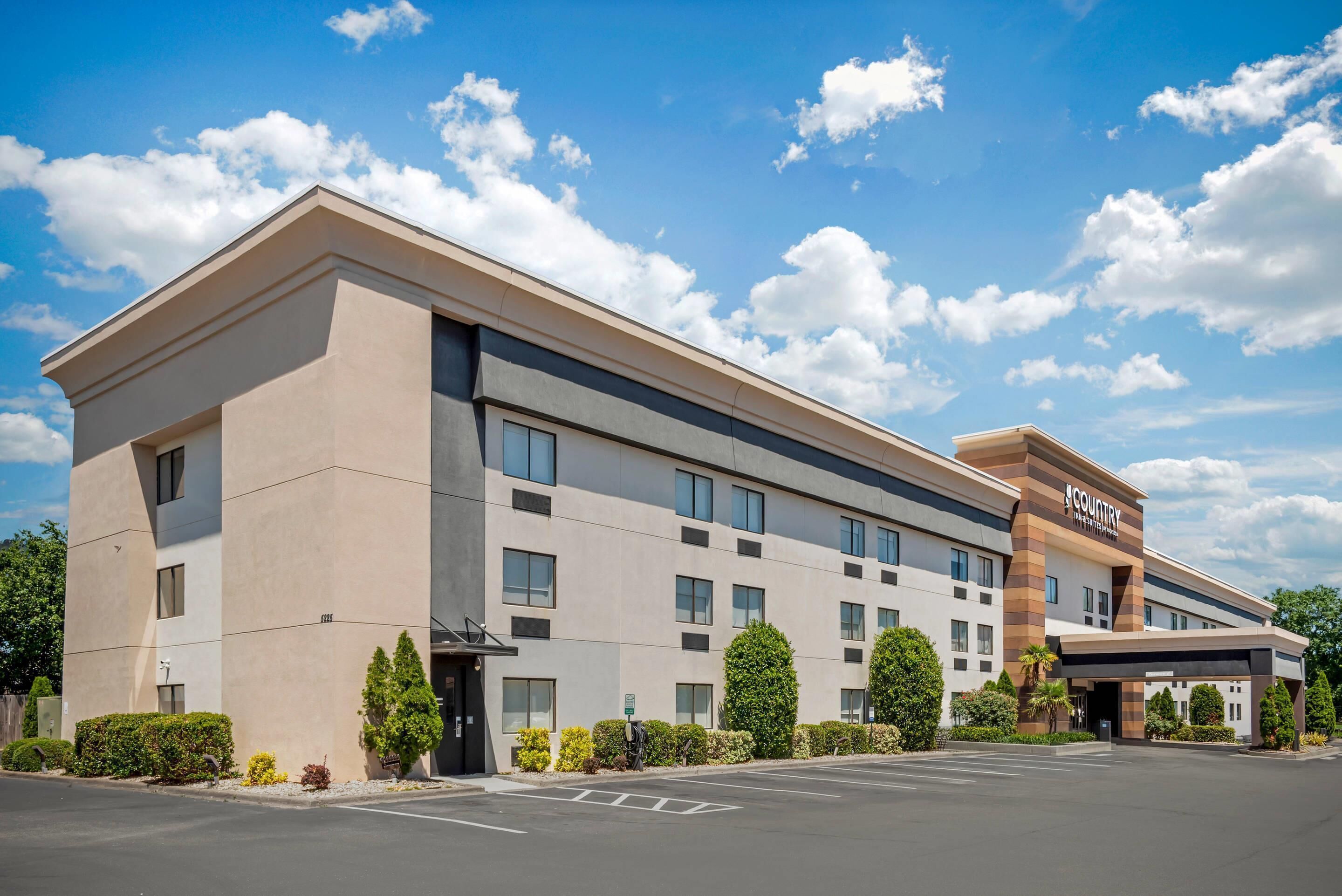 A modern hotel with a flat roof, multiple windows, and a parking lot.