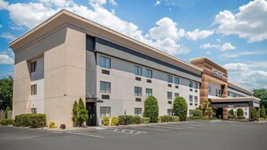 A modern hotel with a flat roof, multiple windows, and a parking lot.