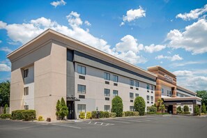 A modern hotel with a flat roof, multiple windows, and a parking lot.