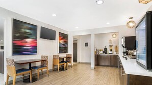 A modern hotel lobby with a dining area, a kitchen, and a bar.