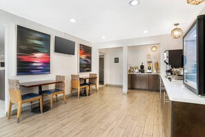 A modern hotel lobby with a dining area, a kitchen, and a bar.