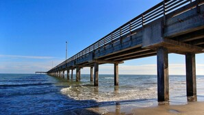 Eine Mole, die sich ins Meer erstreckt, mit blauem Himmel darüber.