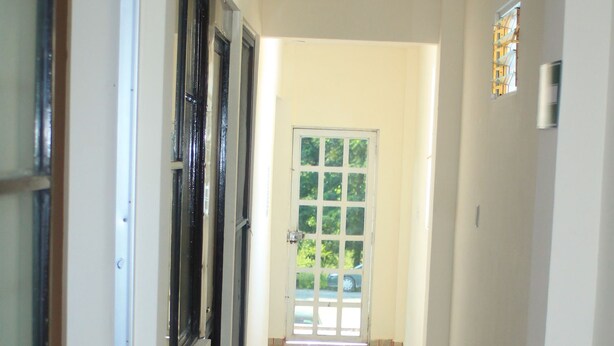 A hallway with tiled flooring, a door at the end, and a window on the left. - Hotel Acuarela Huasteca (Ciudad Valles)