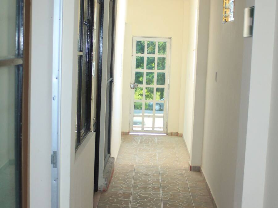 A hallway with tiled flooring, a door at the end, and a window on the left.