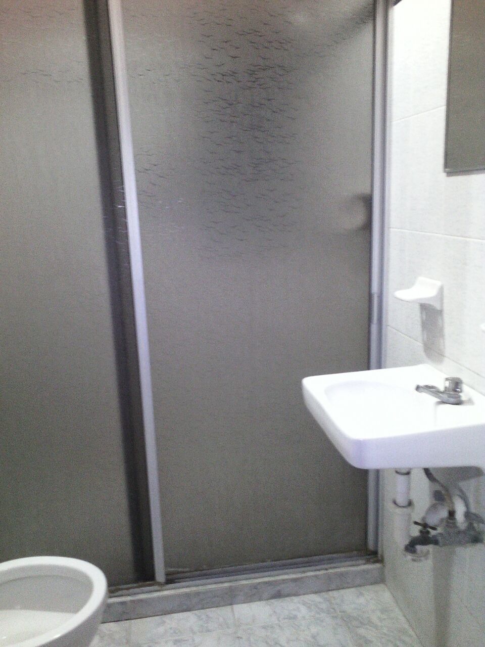 Un baño con ducha, lavamanos e inodoro.