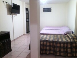Un dormitorio con cama, televisor montado en la pared y cómoda.