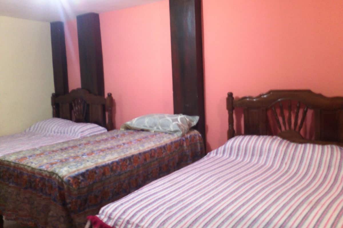 A bedroom with two single beds, each with a wooden headboard and a patterned bedspread.