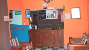 A reception area with a wooden counter, a blue and orange wall, and a checkered floor. - Hotel Acuarela Huasteca (Ciudad Valles)