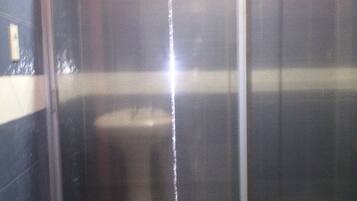 Casa de banho com cabine de duche, sanita e lavatório suspenso.