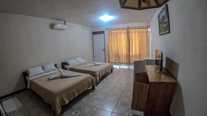A hotel room with two beds, a desk, a chair, a television, and a window with curtains.