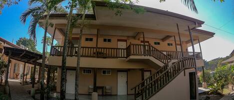 A multi-story building with a central staircase, balconies, and a stone-paved courtyard.