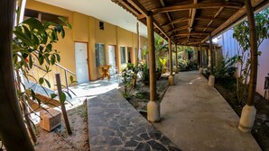 A covered walkway with stone flooring, wooden pillars, and potted plants.