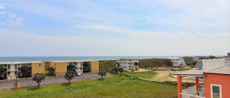 A coastal residential area with a road, buildings, and a view of the ocean.