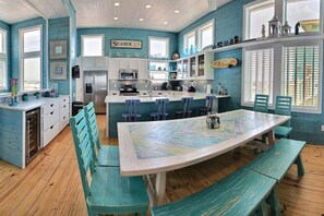 A kitchen with a central island, bar stools, and a dining table with benches. - Sol Mates VW61 (Port Aransas)
