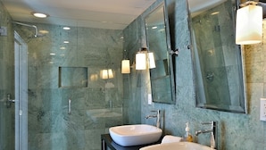 Ein modernes Badezimmer mit zwei Waschbecken, einer Duschkabine aus Glas und großen Spiegeln.