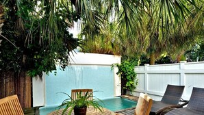 A wooden deck with a pool, lounge chairs, and a table with chairs. - Bahamas House (Key West)