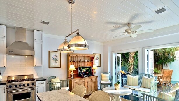 A kitchen with a marble countertop, a stove, and a ceiling fan. - Bahamas House (Key West)