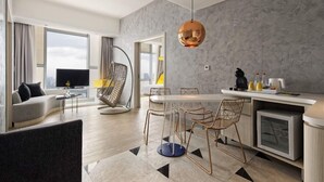 Una sala de estar moderna con sofá, una mesa de comedor con sillas, una zona de cocina con fregadero y encimera, y un ventanal con vistas.