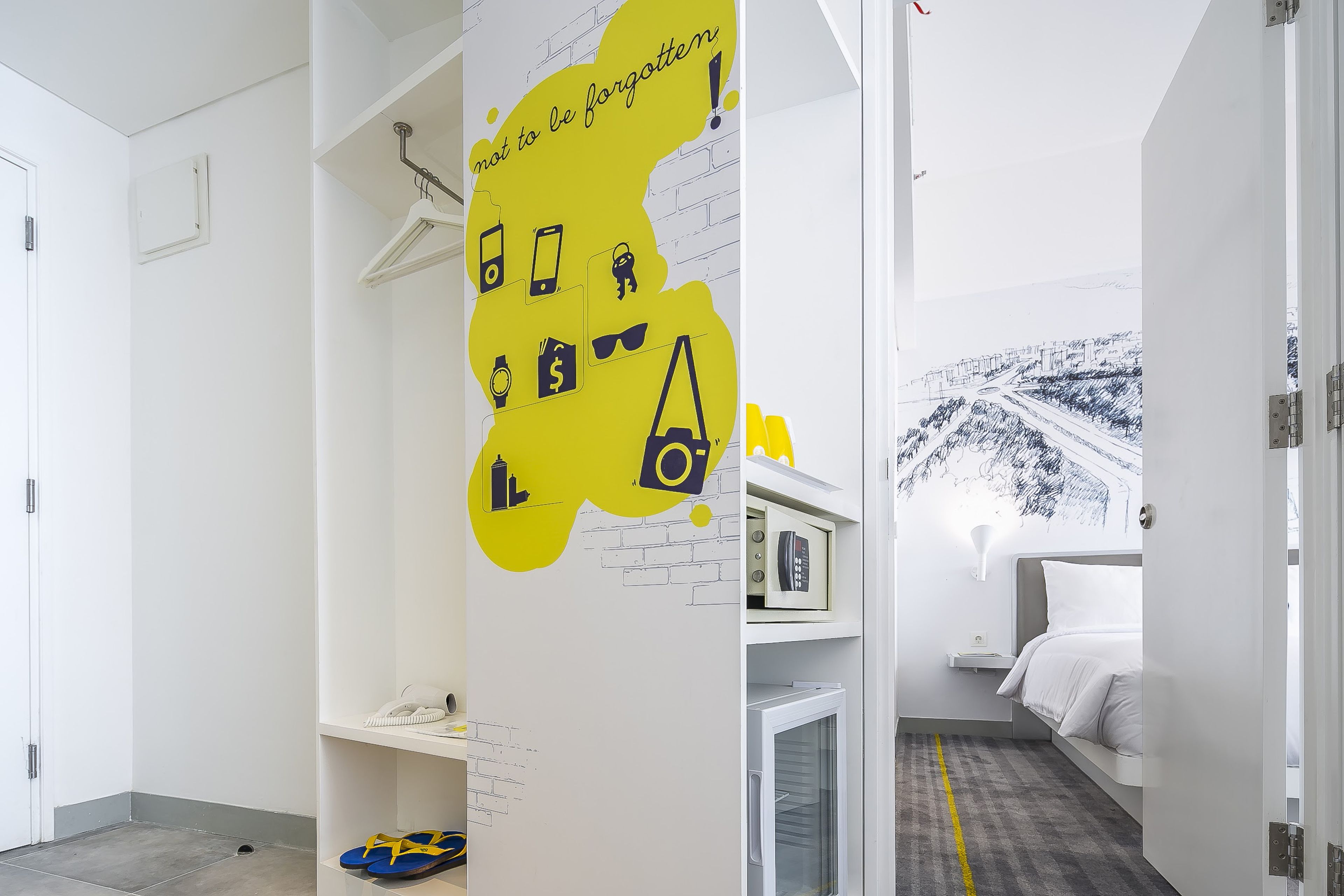 Et moderne hotelværelse med en seng, et lille skrivebord og et garderobeskab.