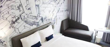 Ein Hotelzimmer mit einem großen Bett, einem Kopfteil, einem Schreibtisch und einem Stuhl.