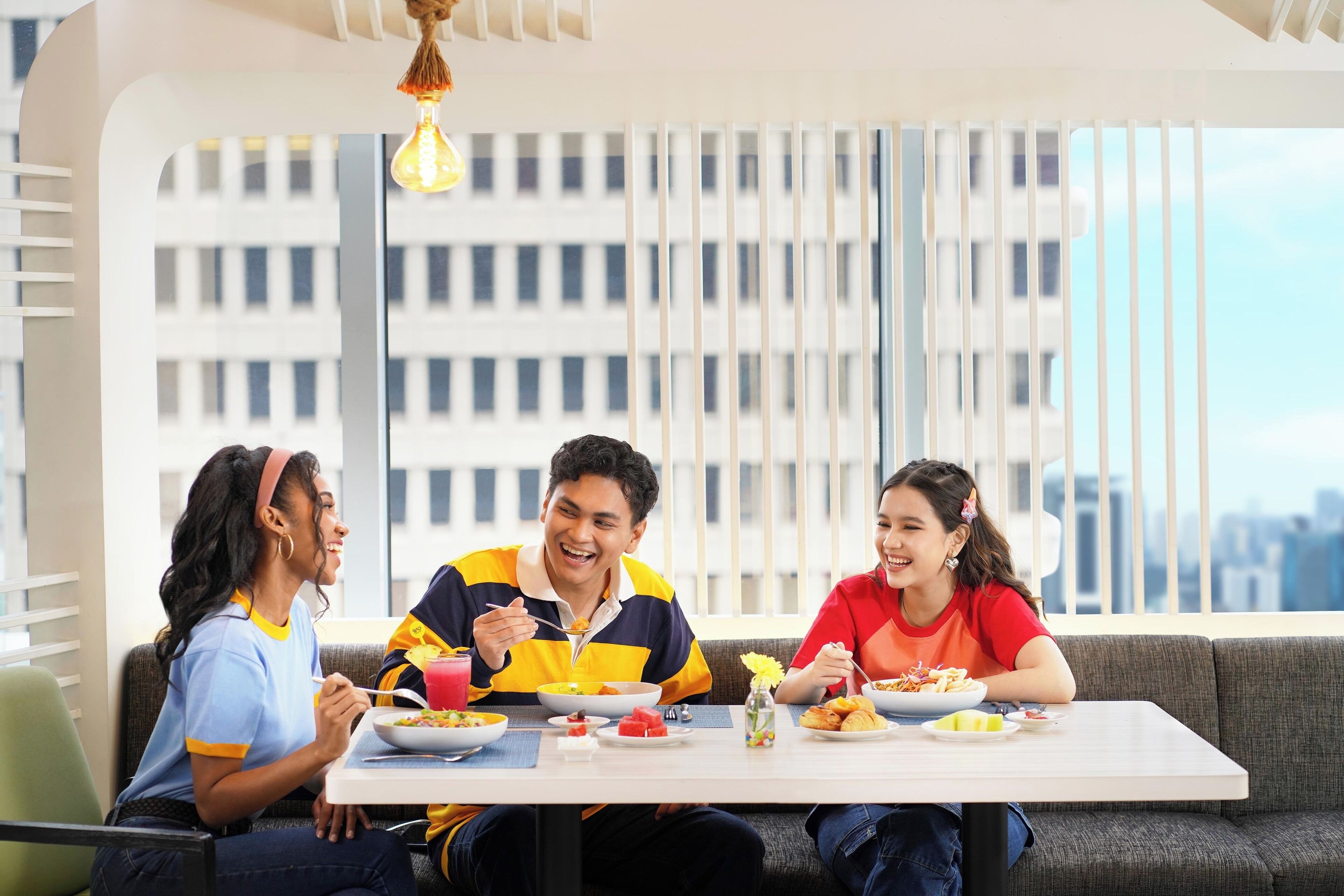 A dining area with a table set for four people, a city view through large windows, and a modern interior design.