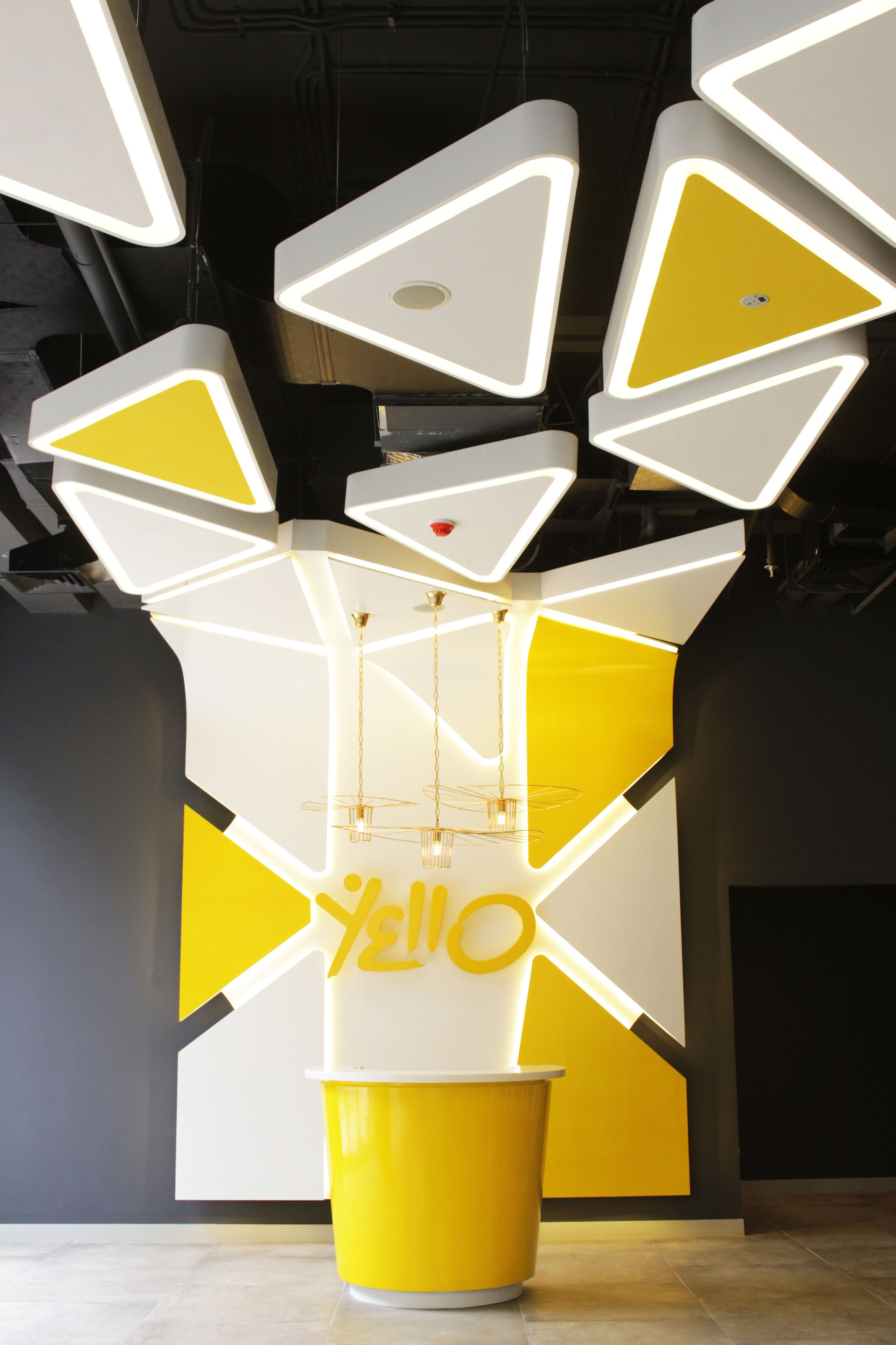 A modern interior with geometric light fixtures and a yellow and white color scheme.