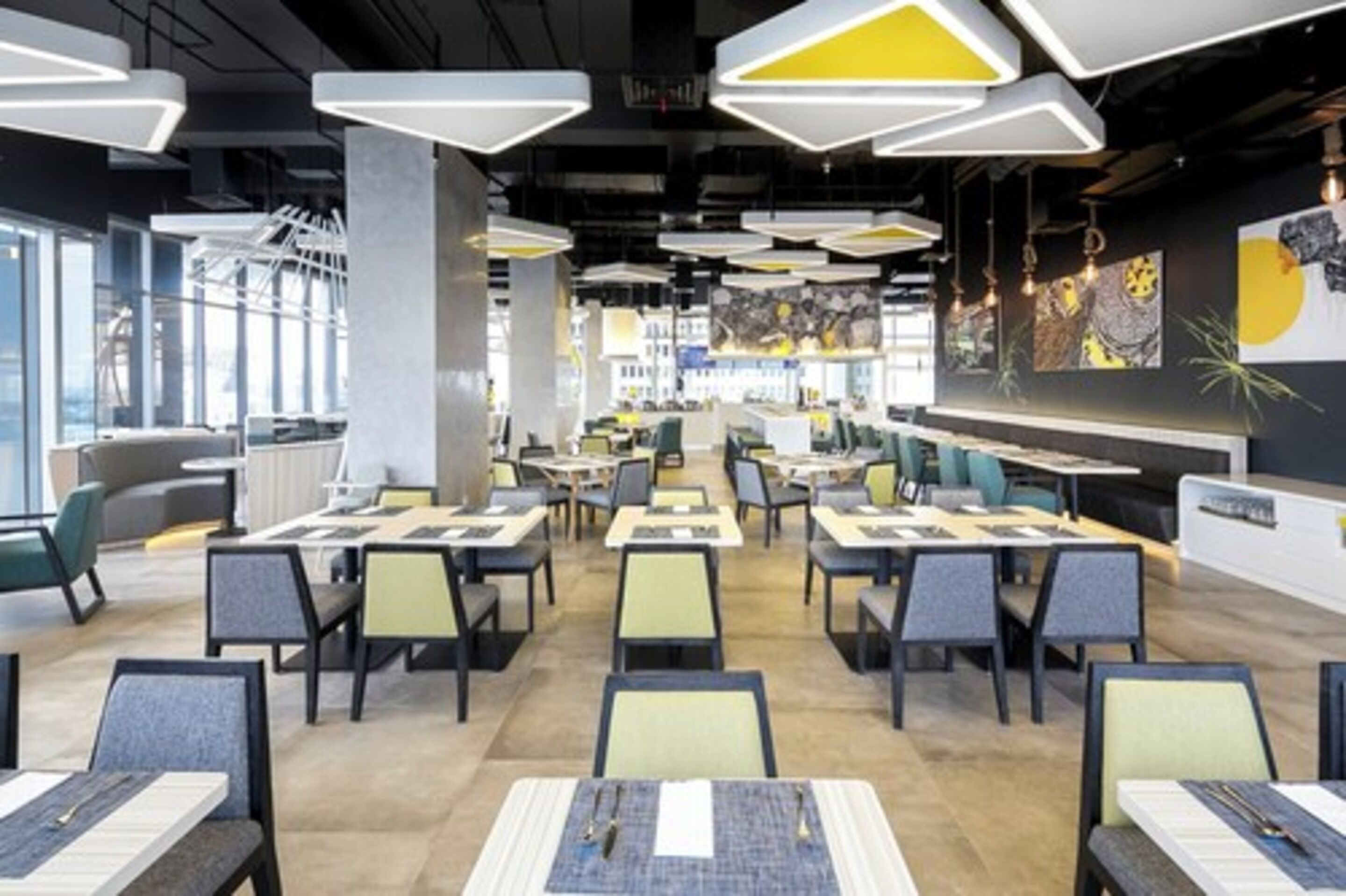 A modern restaurant with high tables and chairs, large windows, and contemporary lighting fixtures.