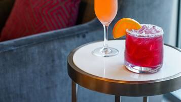 A cocktail on a small round table with a sofa and a patterned pillow in the background.