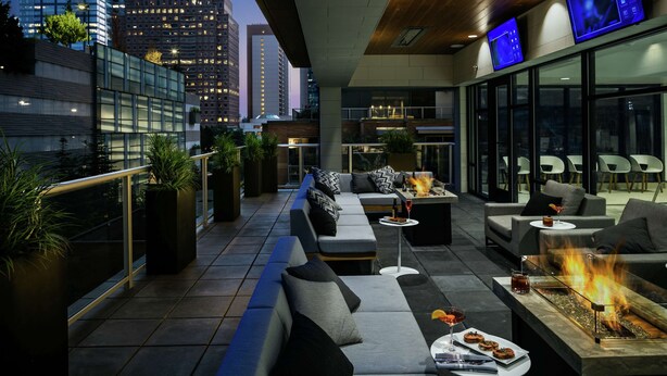 A rooftop lounge with a fire feature, seating, and a city view. - Hilton Garden Inn Seattle Bellevue Downtown, WA (Bellevue)