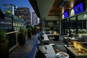 A rooftop lounge with a fire feature, seating, and a city view. - Hilton Garden Inn Seattle Bellevue Downtown, WA (Bellevue)