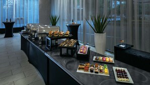 A buffet setup with various food items and a potted plant. - Hilton Garden Inn Seattle Bellevue Downtown, WA (Bellevue)