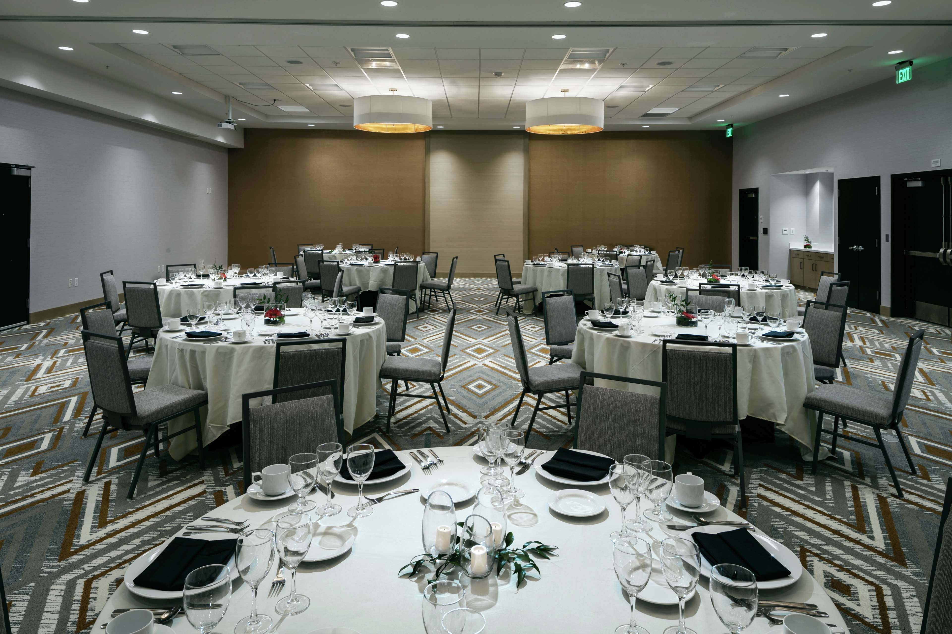 A conference room with round tables, chairs, and a carpeted floor.