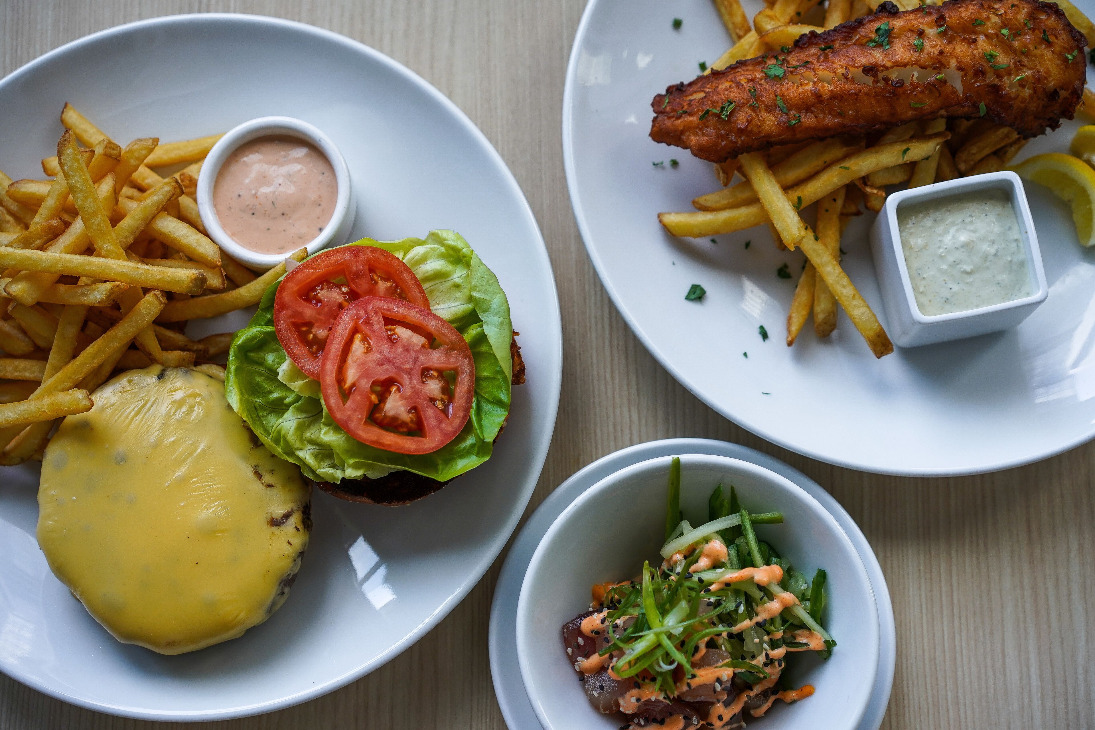 Uma refeição com hambúrguer, peixe, batatas fritas e salada.