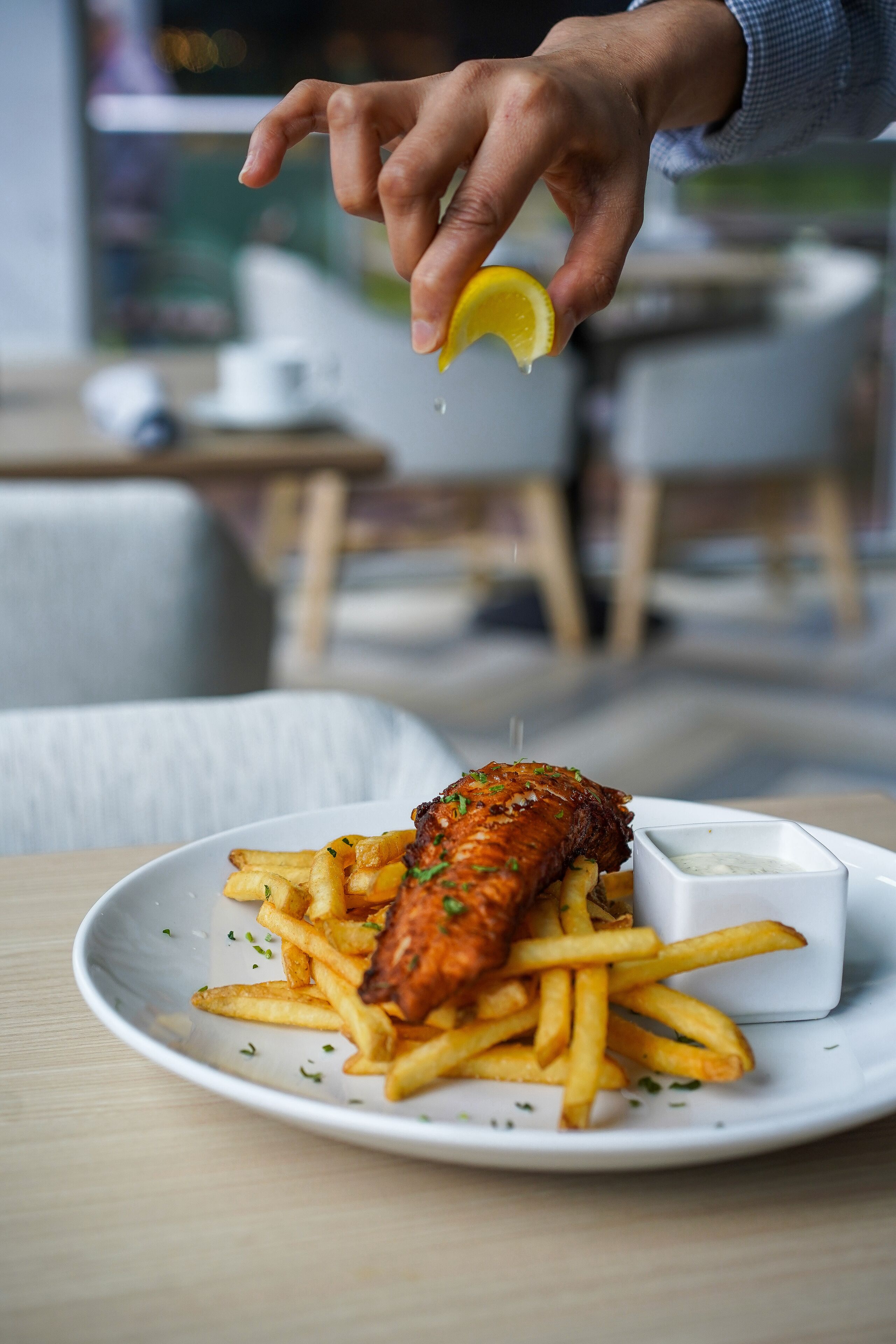 Un plato de pescado con papas fritas y un chorrito de limón.