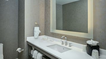 Un baño moderno con un lavabo blanco, un espejo grande y un perchero para toallas.