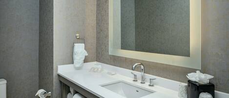 A modern bathroom with a white sink, a large mirror, and a towel rack.