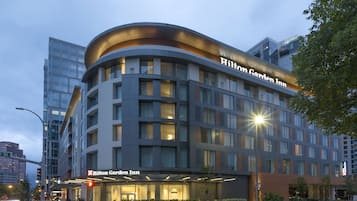 A modern hotel with a curved facade, large windows, and a prominent "Hilton Garden Inn" sign.