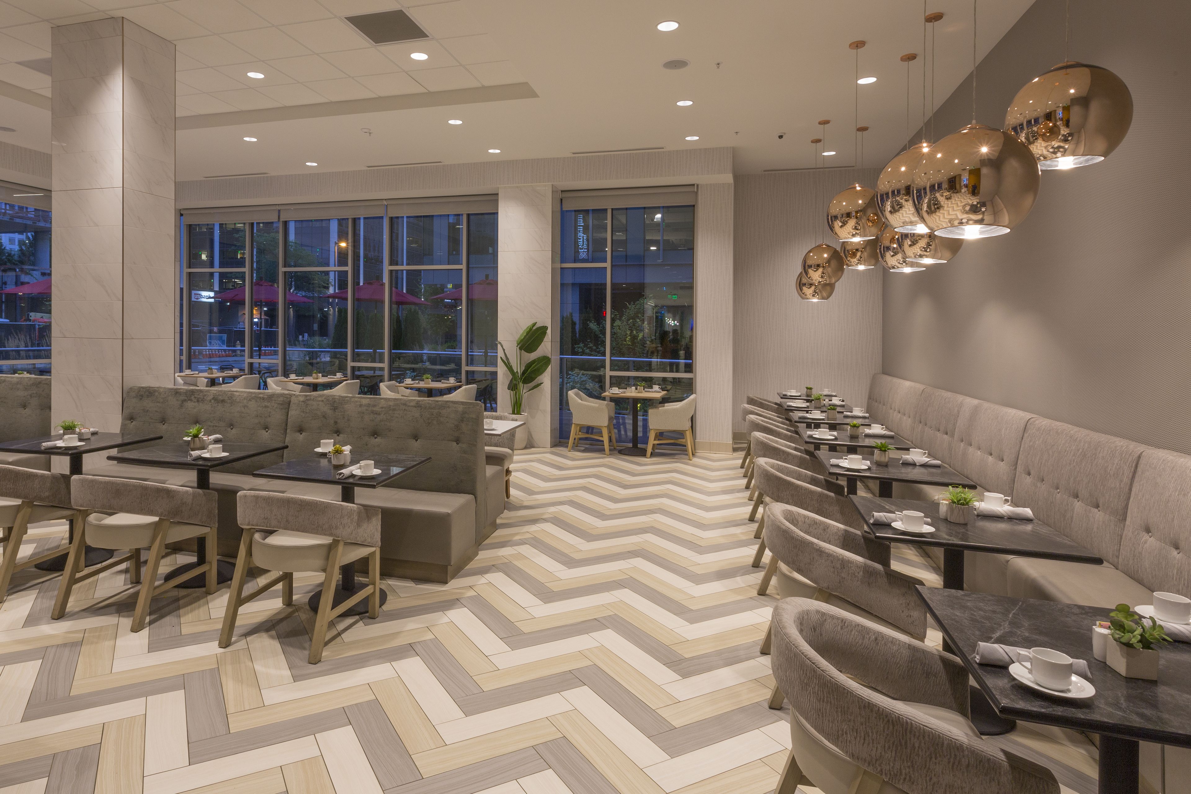 A modern dining area with a chevron-patterned floor, cushioned seating, and tables set for dining.