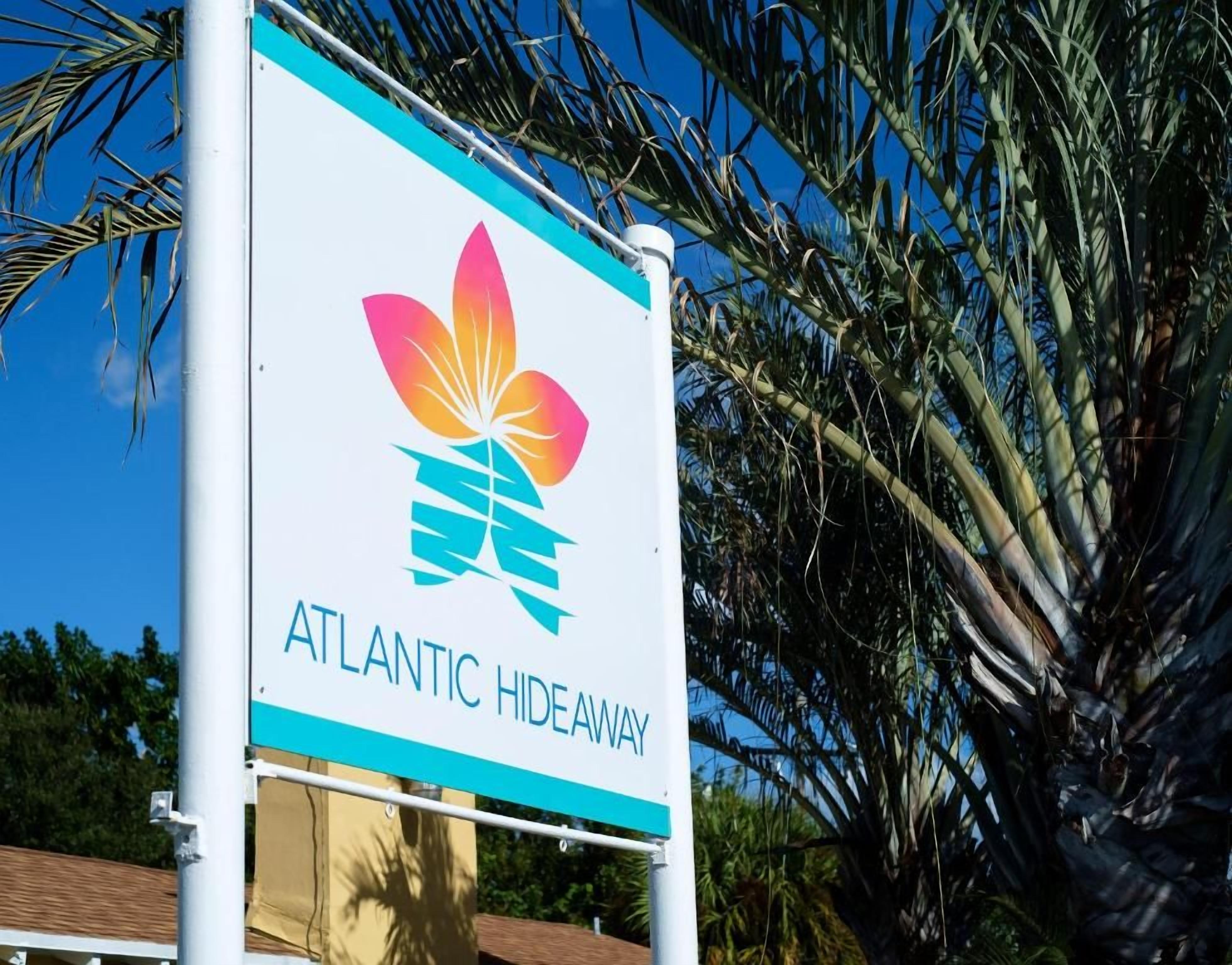 A sign for 'ATLANTIC HIDEAWAY' with a logo featuring a stylized flower and a teal stripe.