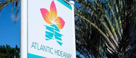 A sign for 'ATLANTIC HIDEAWAY' with a logo featuring a stylized flower and a teal stripe.