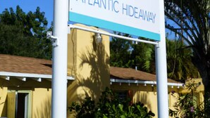 Letrero de Atlantic Hideaway con un logo que muestra una flor y una palmera estilizadas.