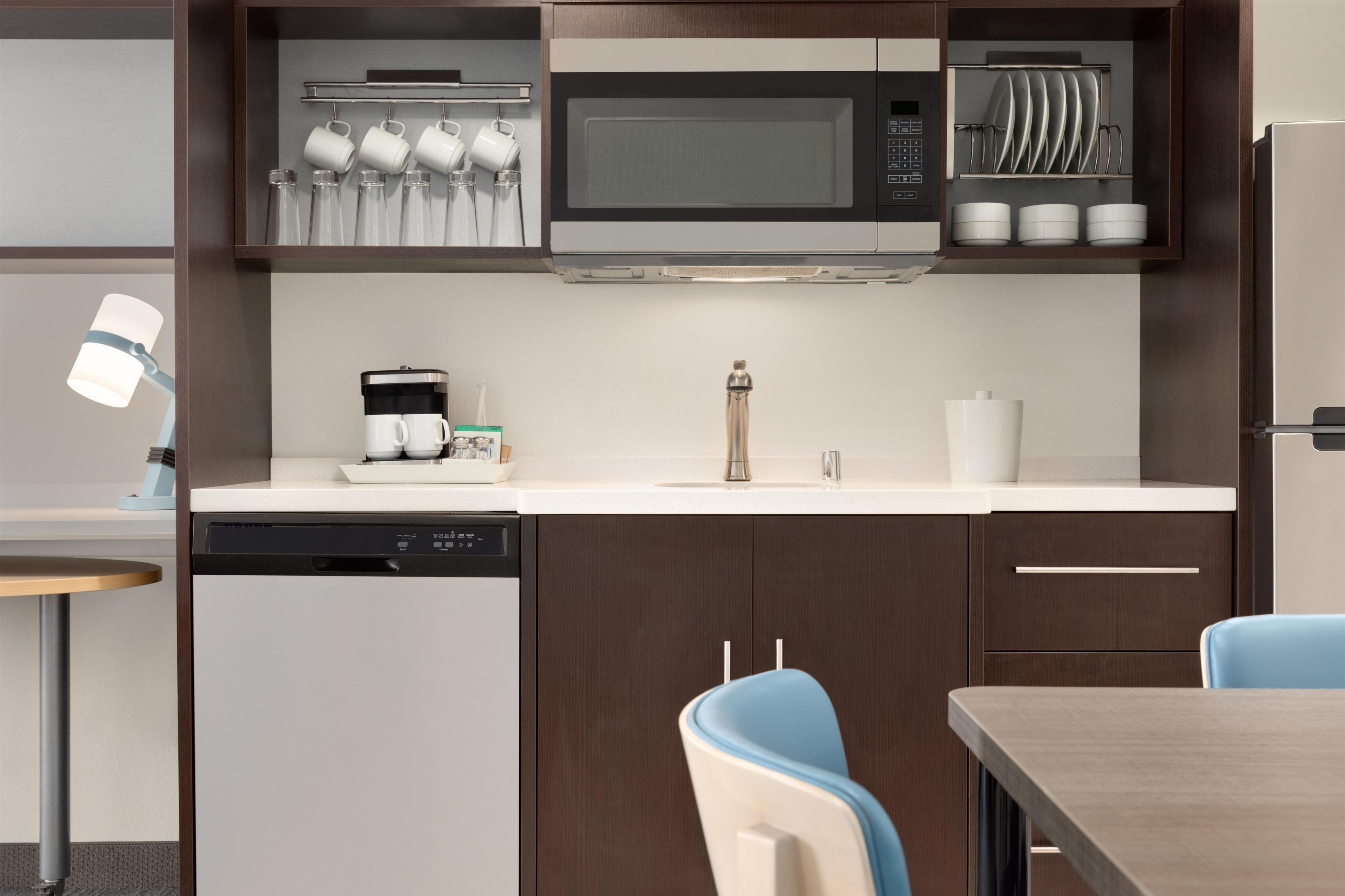 Una cocina compacta con microondas, cafetera y lavavajillas.