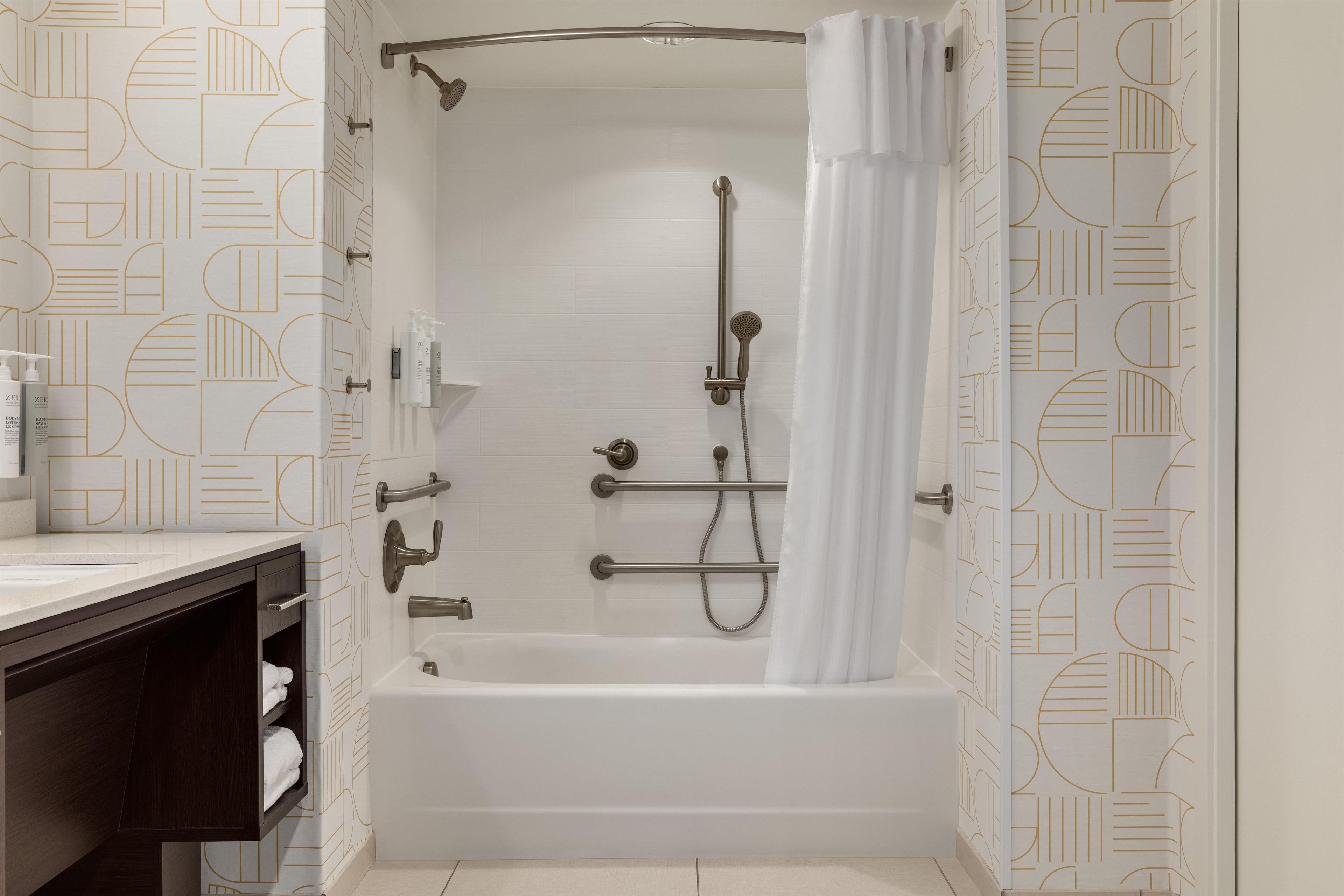 A modern bathroom with a bathtub, shower, and a towel rack.