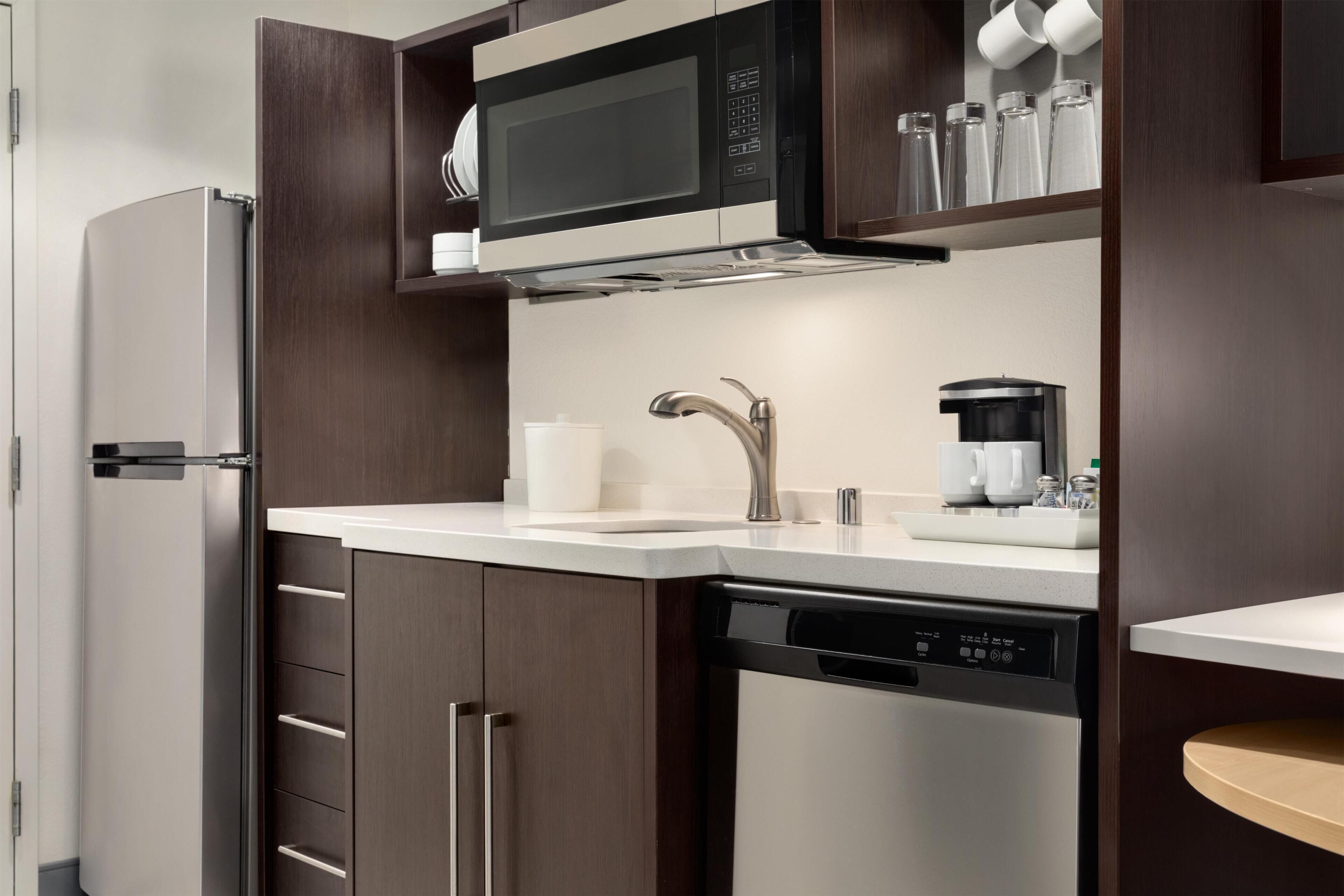 A modern kitchen with a built-in microwave, coffee maker, and dishwasher.
