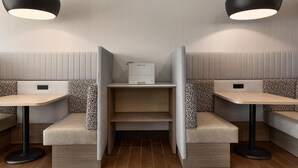 A modern restaurant interior with booth seating, tables, and pendant lighting.